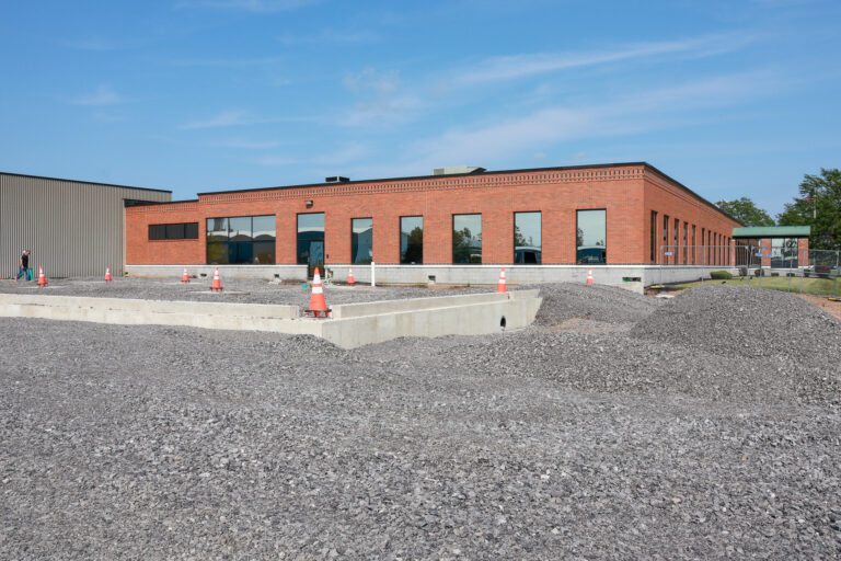 Concrete foundation and graded gravel outside a Sealing Devices brick office building during construction.