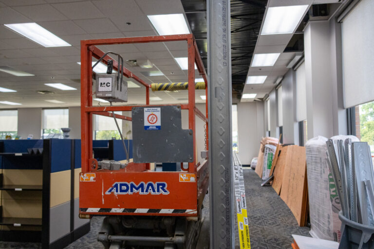 A scissor lift and building materials inside a Sealing Devices office during interior construction.