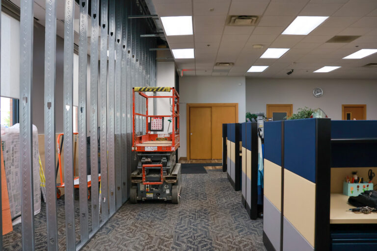 Metal wall framing being installed beside office cubicles during the Sealing Devices expansion.