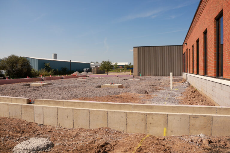 New concrete foundation walls and gravel between Sealing Devices buildings during expansion construction.