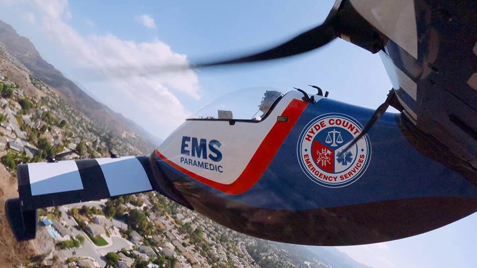 Pivotal eVTOL aircraft with Hyde County EMS markings flying above a coastal community.